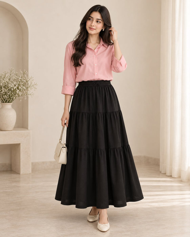 Woman in a pink button down shirt with a long black tiered skirt