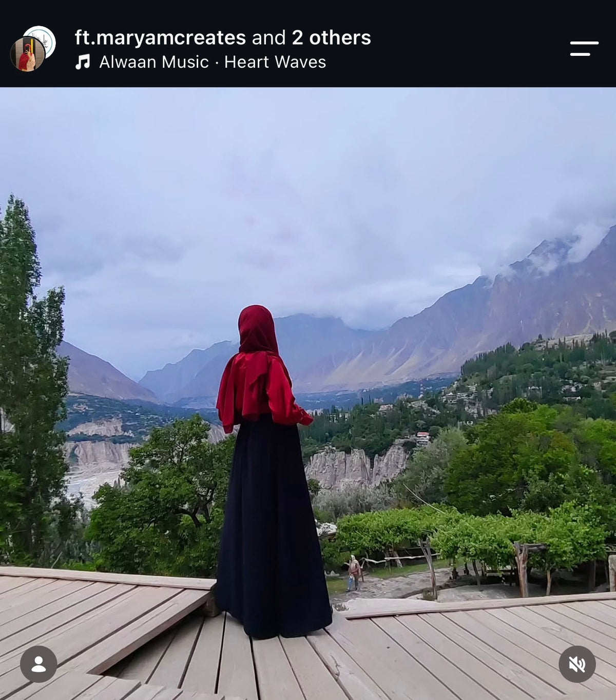 Customer in a red top and long black skirt looking out over a mountain valley