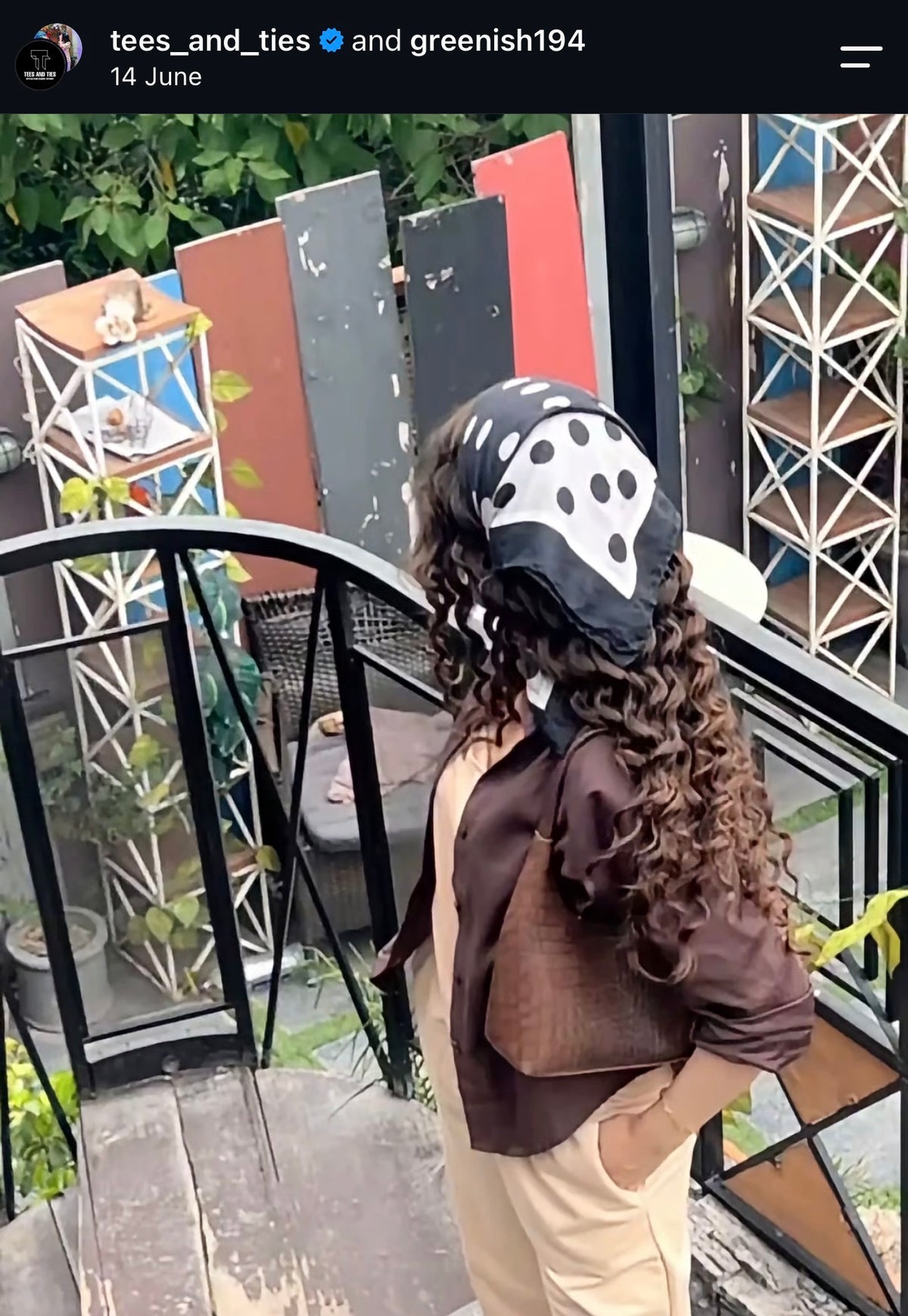 Customer in an olive top and cream trousers with a polka dot scarf and brown bag