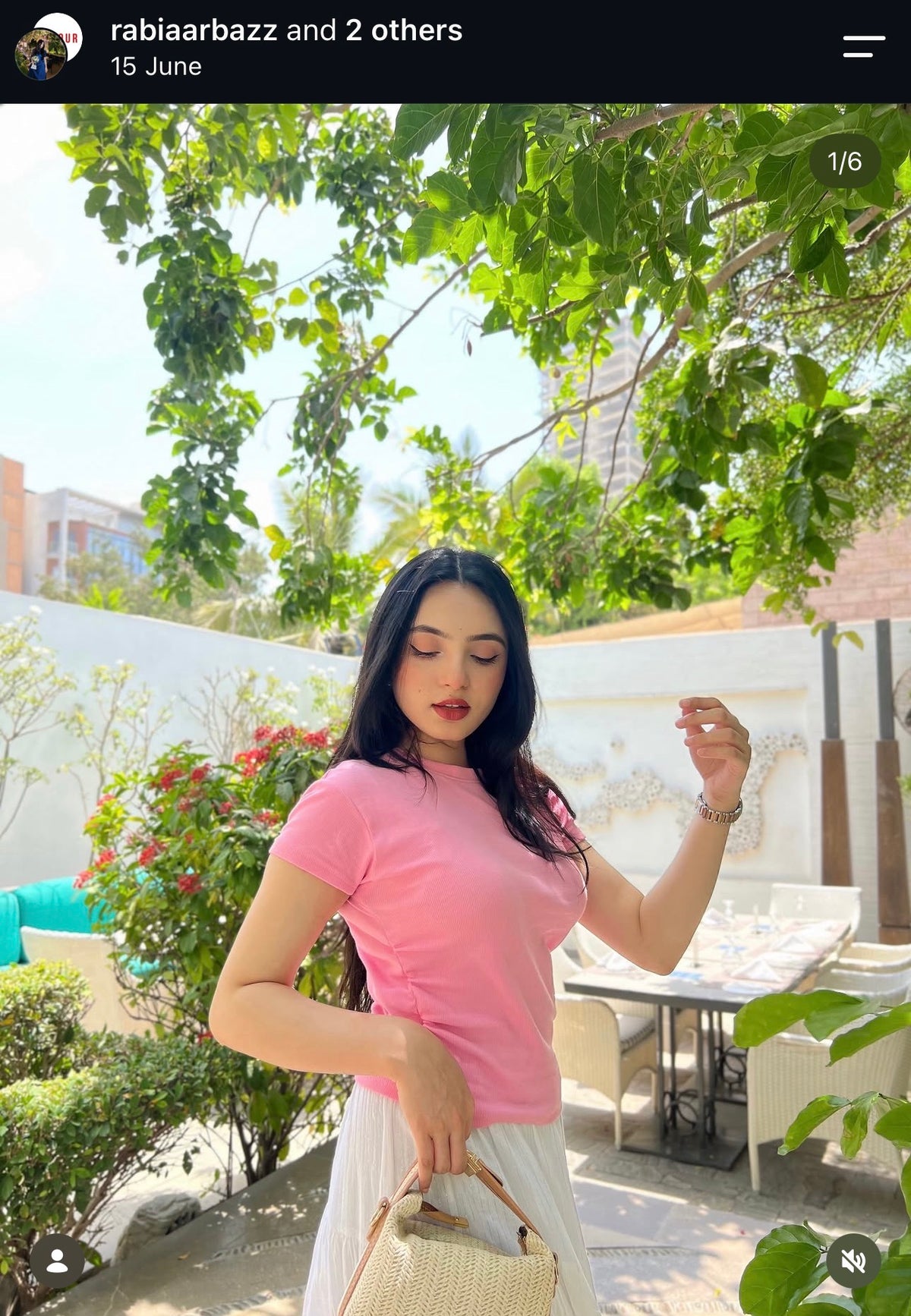 Customer in a pink t-shirt and light trousers holding a straw basket bag