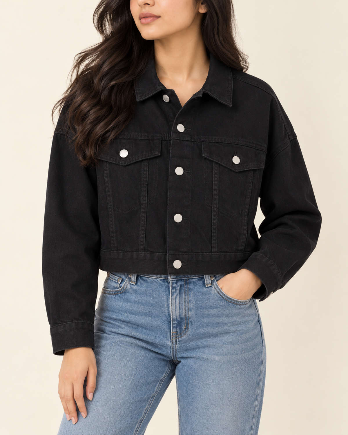 Cropped black denim jacket worn with light blue jeans, front view