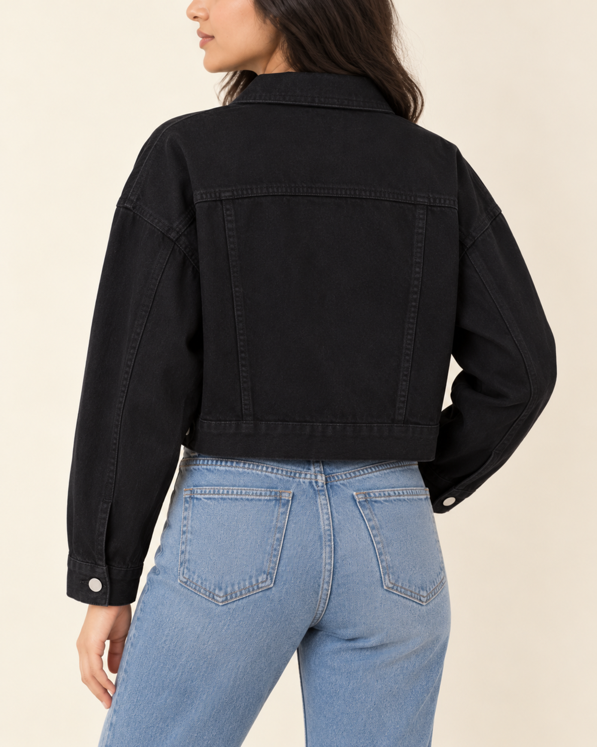 Back view of cropped black denim jacket with light blue jeans