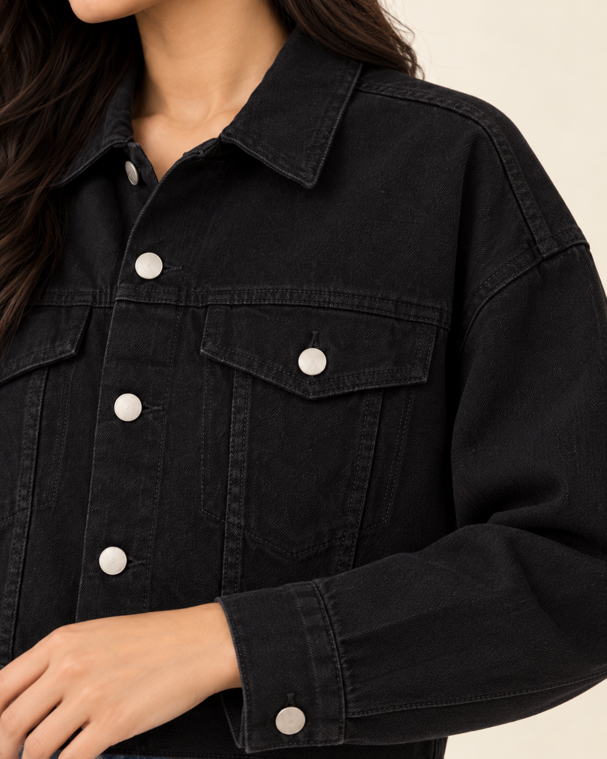 Close-up of black denim jacket chest pockets and silver buttons