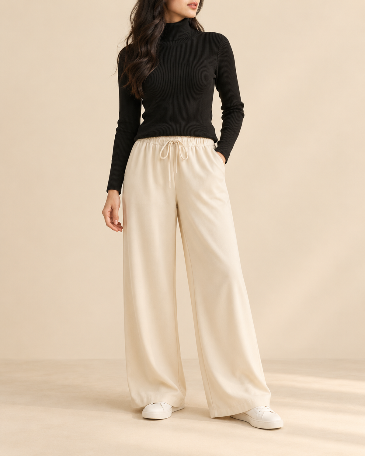 Black ribbed high-neck top with beige wide-leg flapper trousers, front view