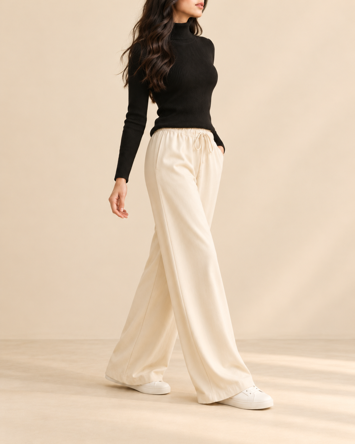 Black ribbed high-neck top and beige flapper trousers, side view