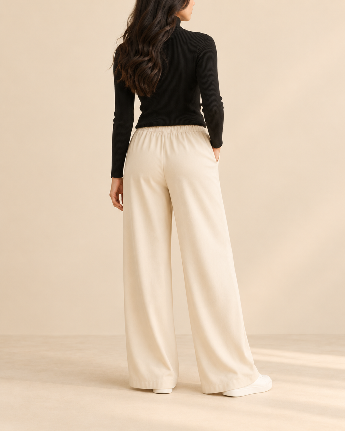 Back view of black ribbed high-neck top with beige flapper trousers