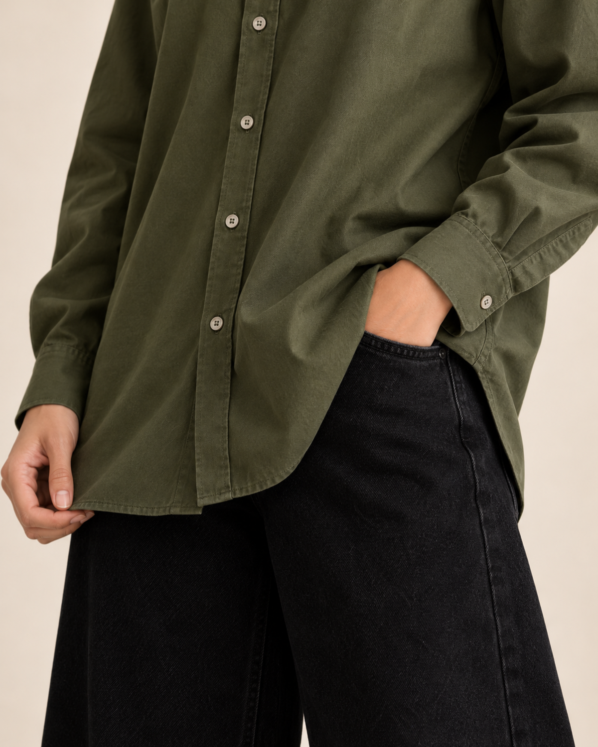 Close-up of olive button-down shirt buttons and hem with black jeans