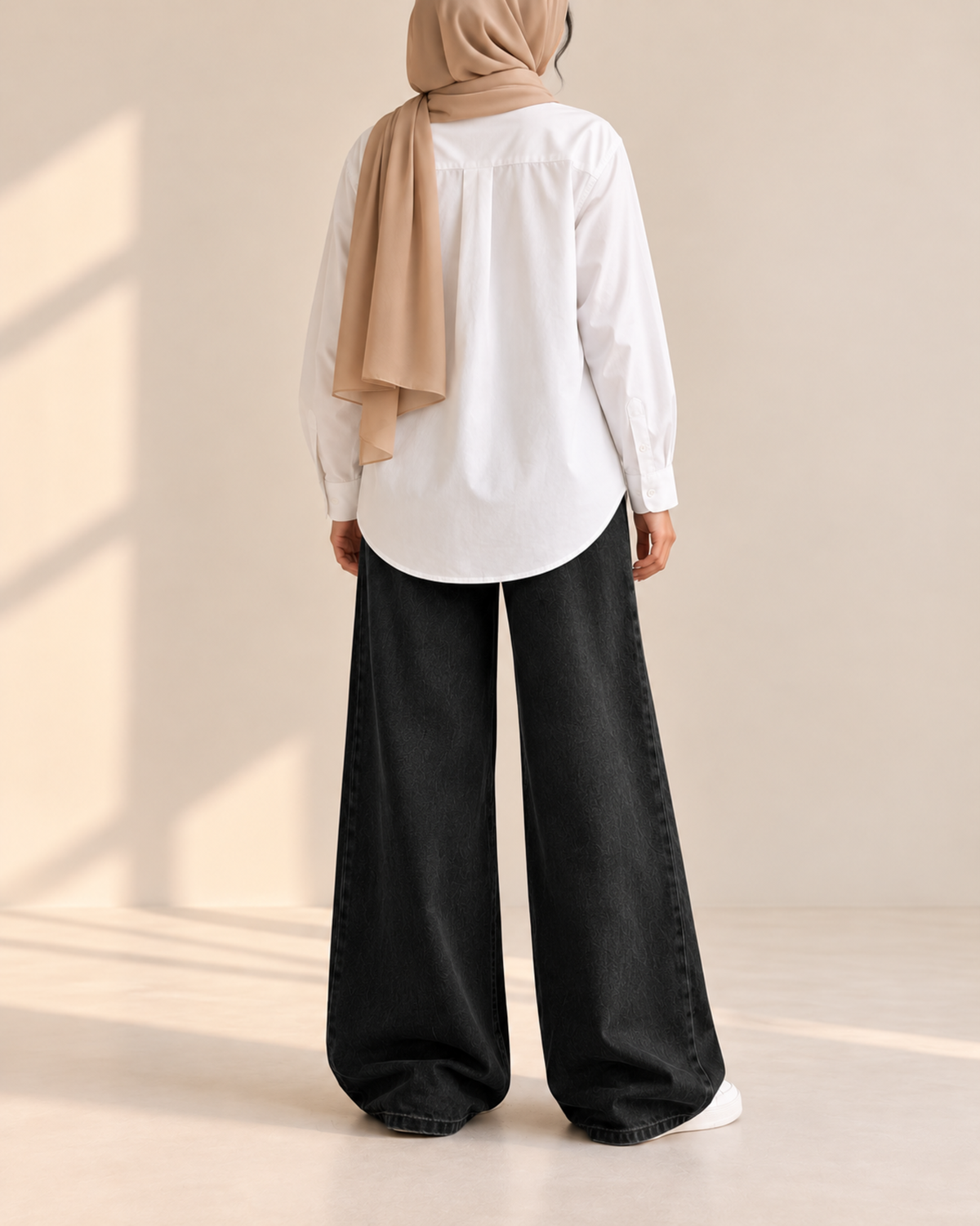 Back view of white button-down shirt with curved hem and black wide-leg jeans