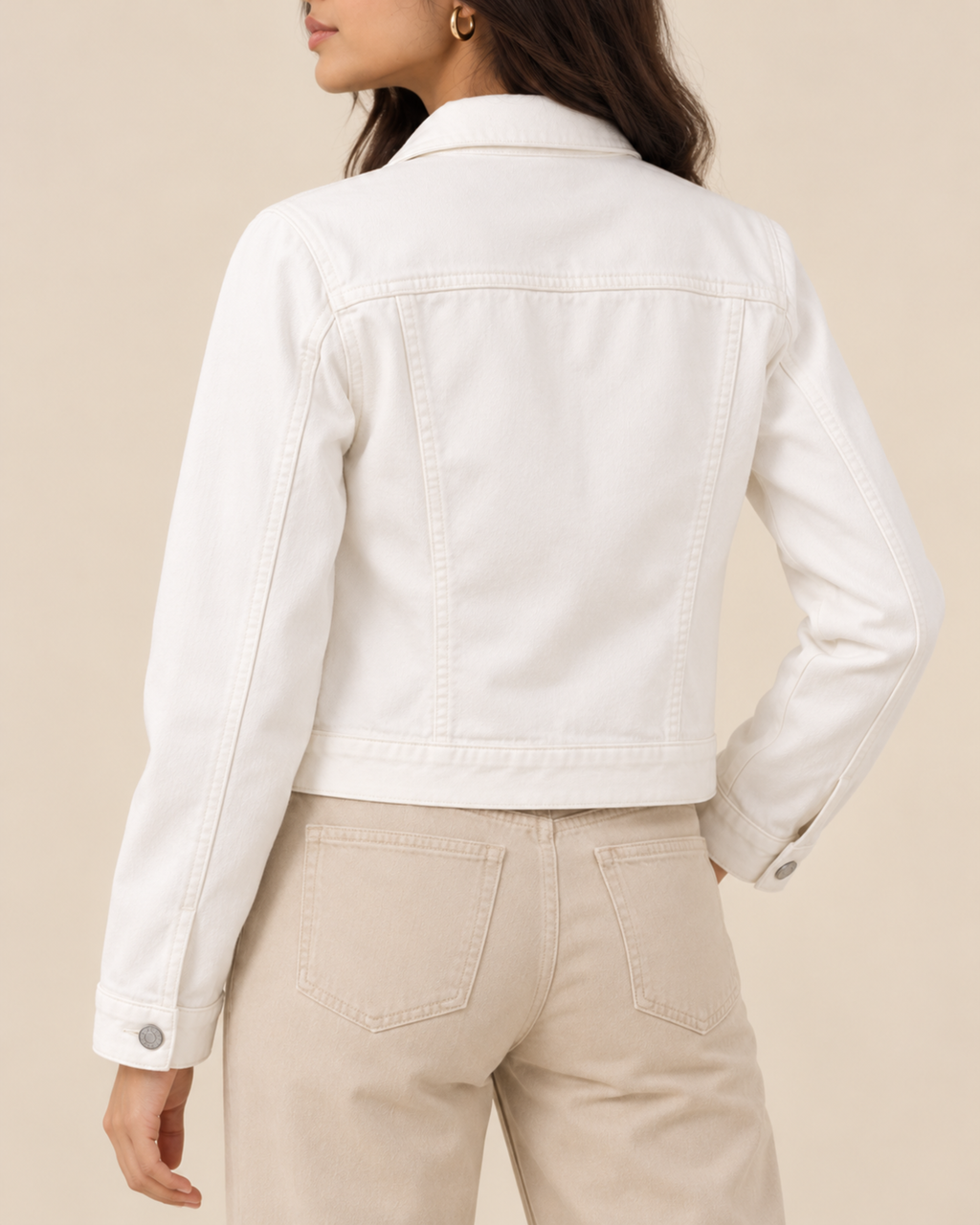Back view of cropped white denim jacket with beige trousers